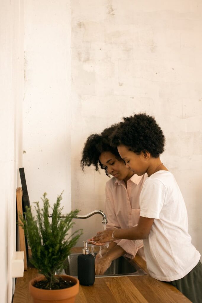 Black mother with son washing hands with soap